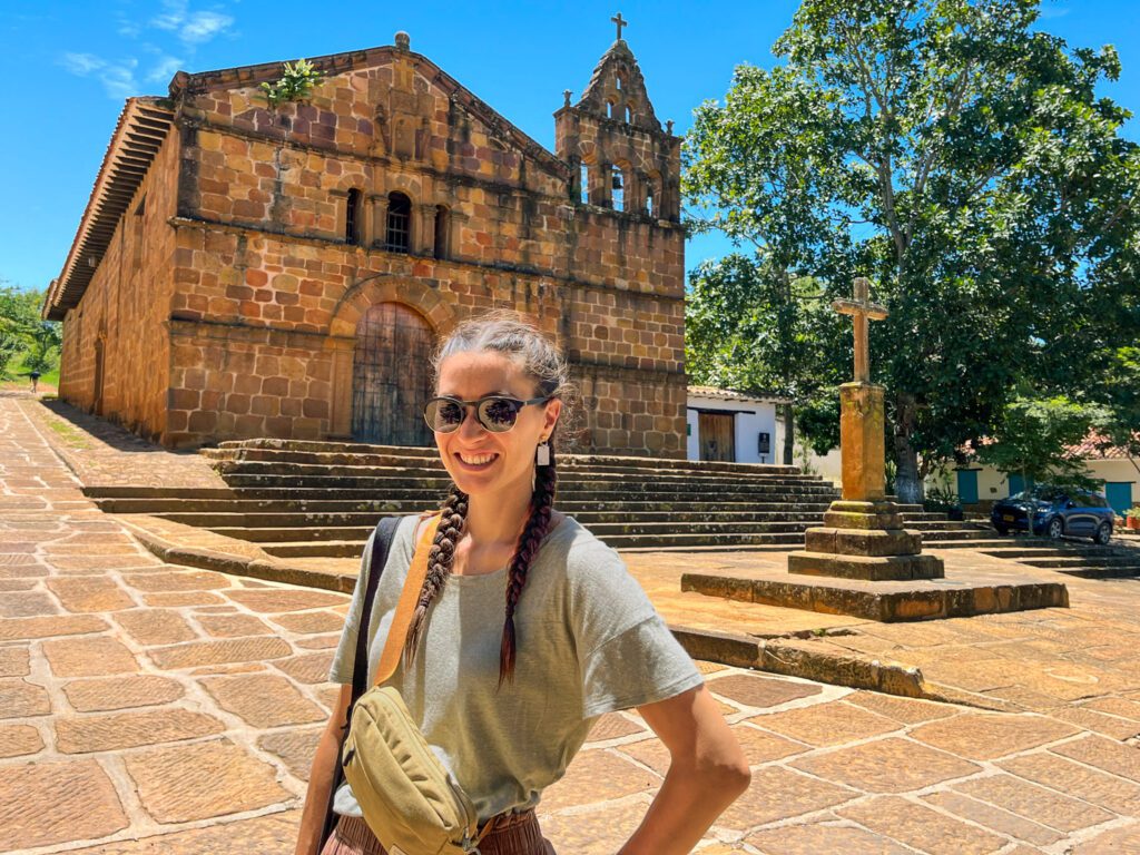 a solo female traveler stands in front of a stone church in barichara, colombia
