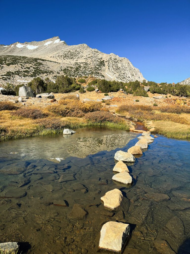 Stepping stones placed in a calm lake in an alpine setting on the bishop pass trail in california