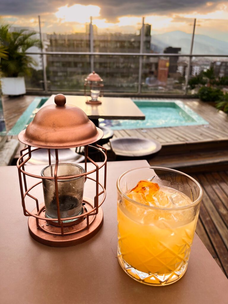 a traveler enjoys cocktail on a rooftop bar while staying in a hostel in colombia
