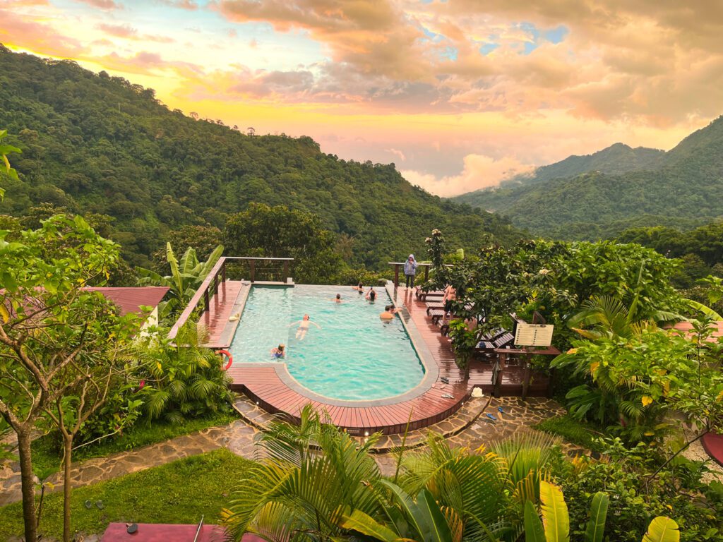 a hostel’s infinity pool overlooking the mountains during sunset.