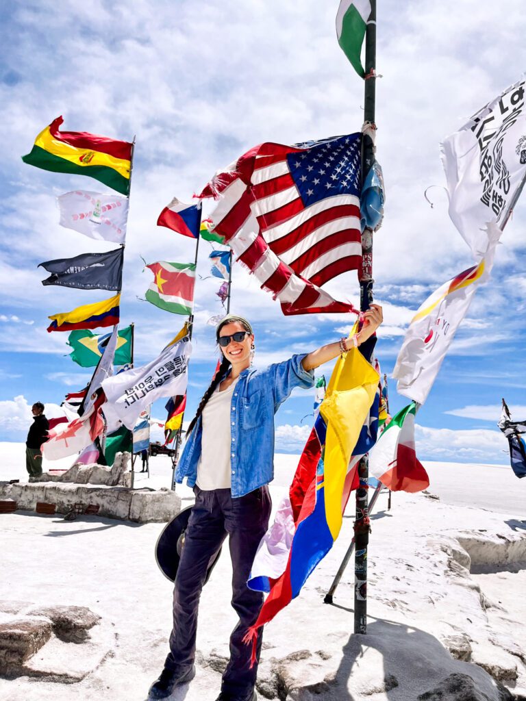 a traveler stands at a salt flat with flags