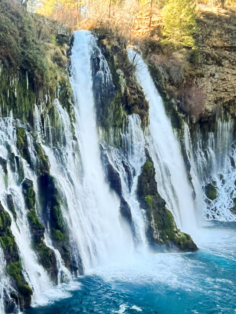a large waterfall and turquoise basin of water