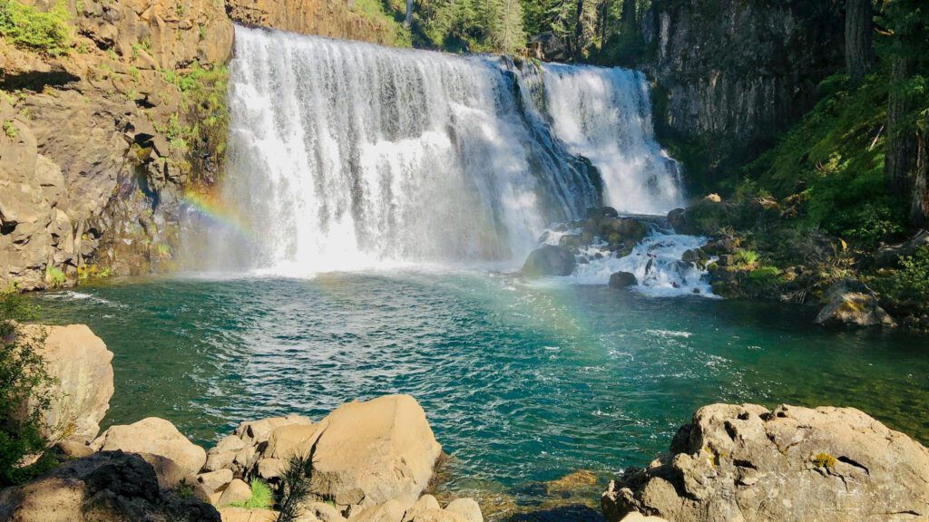 a wide waterfall cascading into a turquoise basin of water