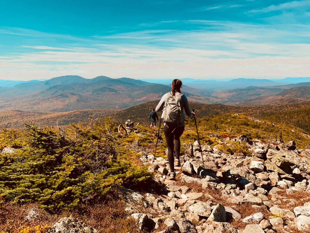 a day hiker with a backpack and trekking poles on a trail in Maine