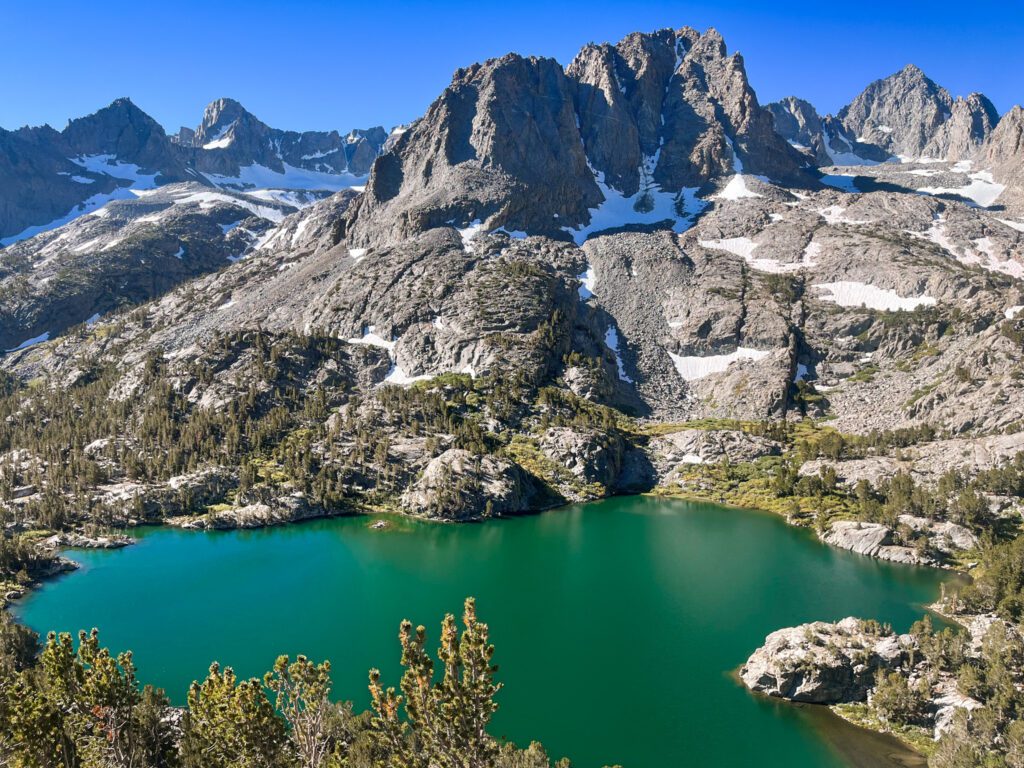 Aerial view of a turquoise alpine lake and dramatic granite mountains.