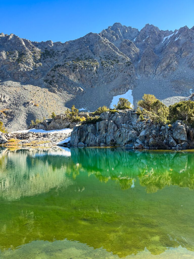 a pristine emerald-green alpine lake on the bishop pass hike in california