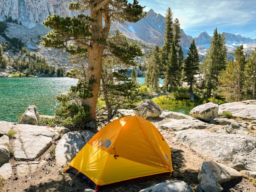 a tent pitched at a campsite next to an alpine lake