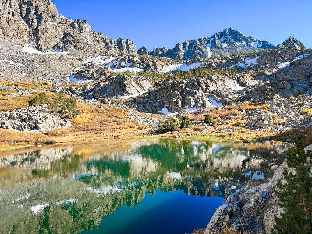 a teal-blue alpine lake in a basin of granite mountains along the chocolate lakes and bishop pass trail