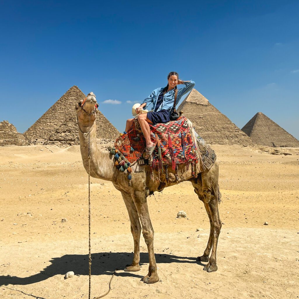 a traveler on a camel in front of the pyramids in Egypt.