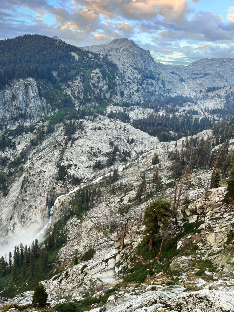 a roaring river cascades down a valley on the lakes trail hike