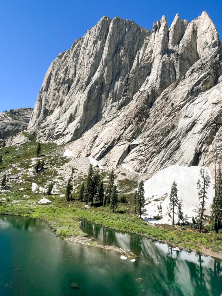 lower hamilton lake, an emerald green alpine lake and a tall granite wall next to it.