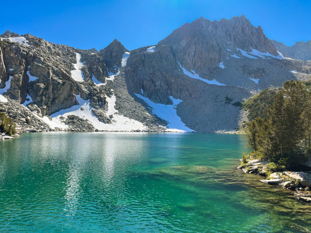 Midnight Lake, a deep turquoise alpine lake in California’s eastern sierra with craggy mountains towering over it.
