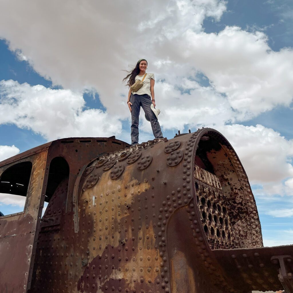 a traveler wearing a minimalist travel outfit stands on top of an abandoned train.
