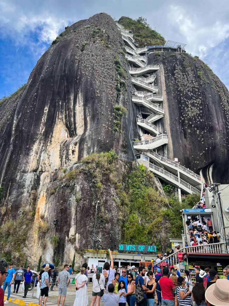 tourists waiting in a line to ascend to the top of a giant monolith