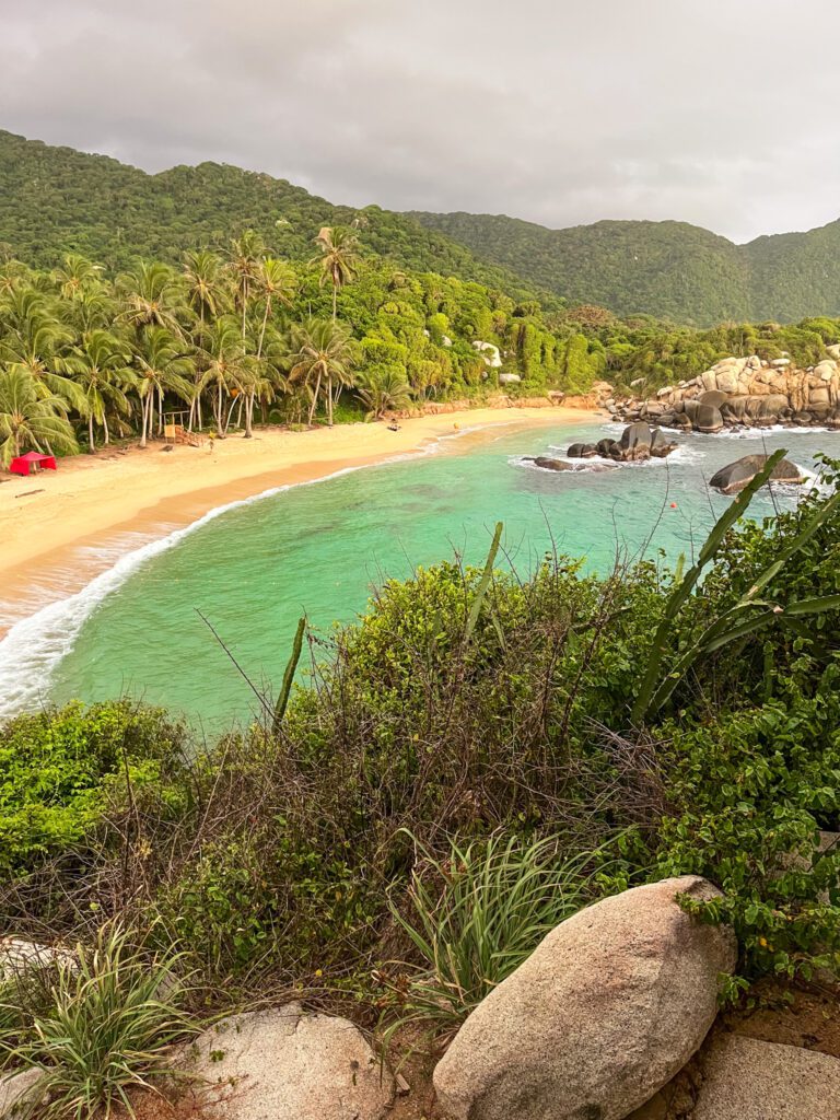 a tropical beach in colombia with turquoise water and smooth boulders